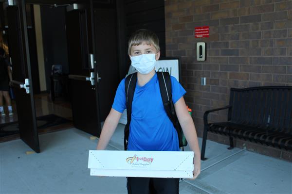 student holds box on first day of school